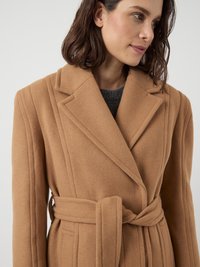 Camel wool coat with a belted waist, lapel collar, and textured fabric. Features horizontal stitching details and a tailored fit.