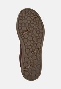 Brown rubber shoe sole with circular textured patterns. "CAMPER" branding visible in multiple locations. Size marked as 42.
