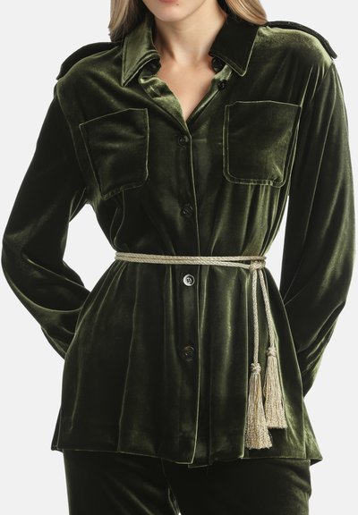 Camicia in velluto verde con due tasche frontali, design con bottoni, spalline e una cintura intrecciata in oro con frange.