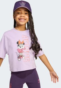 Lilla lühike t-särk, millel on Minnie Mouse'i graafika roosas kapuutsiga, koos tumepurpursete retuusidega, millel on Adidas'i logo.