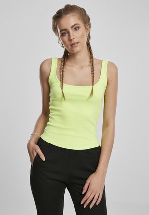 Débardeur jaune néon avec un décolleté carré et des bretelles fines, coupe ajustée qui met en valeur la taille. Assorti à un pantalon noir.