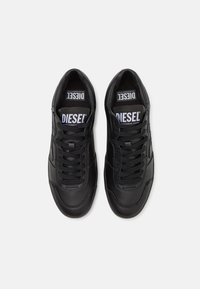 Sneaker neri realizzati in pelle liscia. Le caratteristiche includono lacci piatti, punta arrotondata e loghi bianchi sulla linguetta e sui pannelli laterali.