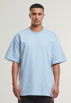 T-shirt surdimensionné bleu clair en coton avec des manches courtes et un col rond. Présente un petit logo blanc imprimé sur la poitrine.