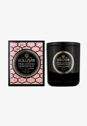 Sort kokosvokslys i en stilren glasbeholder med en guld- og sort etiket. Lyserød geometrisk mønsterboks med logo og produktinformation.