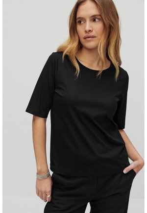 Svart t-shirt med kort ärm i ett mjukt tyg och klassisk rund halsringning. Har en avslappnad passform och subtila sömdetaljer.