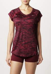 Camiseta deportiva a rayas rojas y negras con mangas en forma de capucha, cuello en V y un logo sutil. Combinada con pantalones cortos color burdeos, mostrada de frente.
