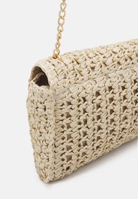 Borsa in paglia intrecciata di colore crema con forma rettangolare. Caratterizzata da una trama a treccia e una tracolla in catena dorata per il trasporto.