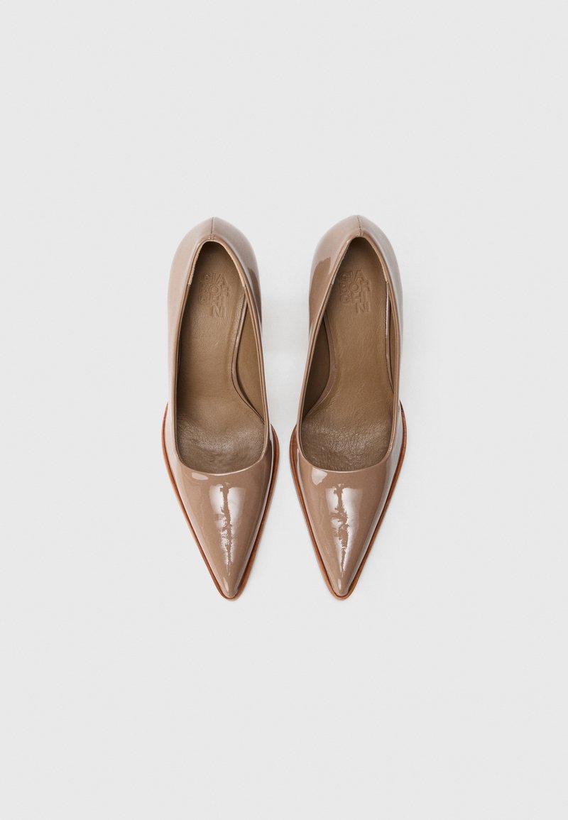 Chaussures à talons aiguilles en cuir verni nude avec bouts pointus, texture lisse et semelle intérieure en cuir marron. Design classique de pompes.