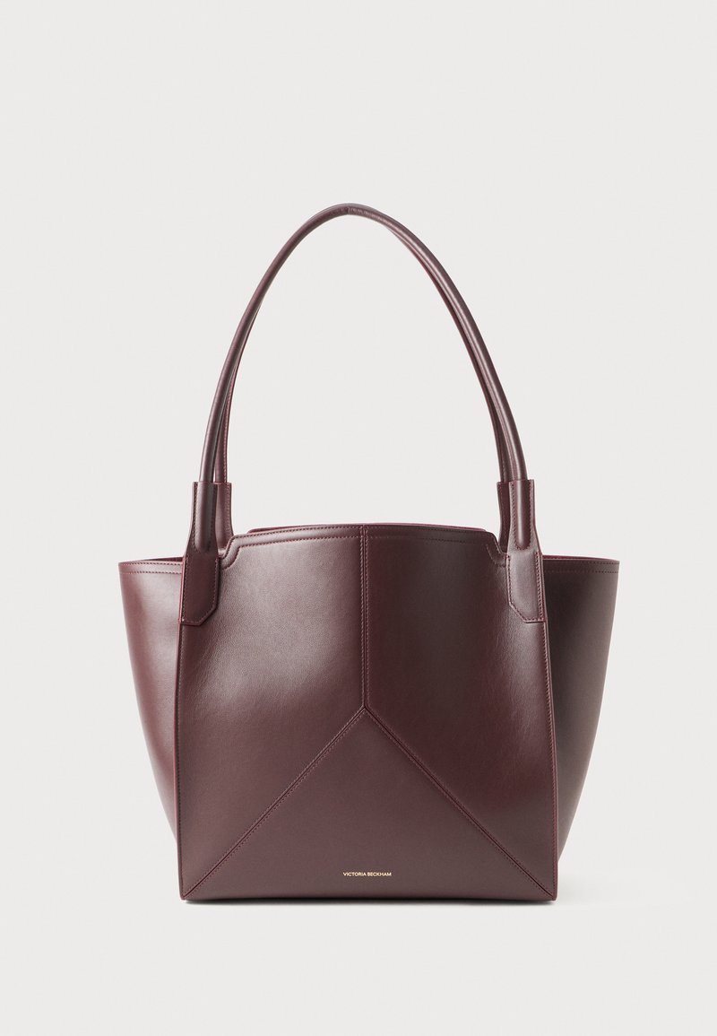 Dark brown leather tote bag with two handles and geometric panel stitching, featuring small gold brand text near the bottom center.