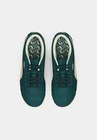 Πράσινα σουέτ αθλητικά παπούτσια με υφή, διακοσμημένα με σκούρες κορδόνες, κρέμα χρώματος επένδυση και σχέδιο στο εσωτερικό με το λογότυπο της μάρκας.