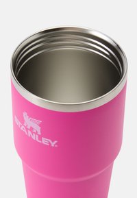 Ružový izolačný pohár s nerezovým okrajom, s matným povrchom a bielym logom "Stanley" na boku.