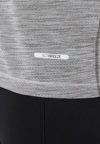 Top atletico grigio con un design testurizzato e melangiato. Presenta un'etichetta bianca "ACTIBREEZE" e cuciture a contrasto. Parte inferiore nera visibile.