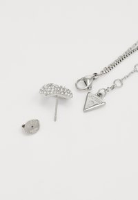 Silberner Schmuckset mit einem Ohrstecker, der mit klaren Strasssteinen verziert ist, und einer Kettenhalskette mit einem dreieckigen Anhänger und einem Karabinerverschluss.