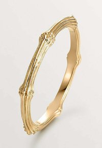 Pulsera de oro con un diseño texturizado similar al hueso. Presenta bordes suaves y una forma circular continua.