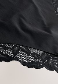 Tissu en satin noir avec un bord festonné orné de détails en dentelle noire élaborée. La texture est lisse, contrastant avec le motif ouvert de la dentelle.