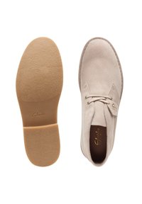 Beige mockasin med snörning, rund tå och en mjuk tanfärgad gummisula. Innehåller subtil logotyp på sidan och i innersulan.
