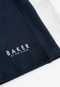 Bavlněné tričko s námořnickomodrými a bílými sekcemi, s logem "BAKER BY TED BAKER" v bílé barvě na námořnickomodré. Měkká textura a čistý design.