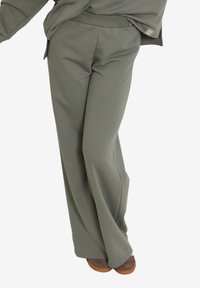 Lekkie, proste spodnie w kolorze oliwkowym, charakteryzujące się miękką teksturą, elastycznym pasem oraz minimalistycznym designem.