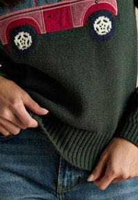 Roheline kudumipusa, millel on roosa auto disain, tekstureeritud kangas, soonikserv ning kontrastsed sinised ja valged tikitud ratad.