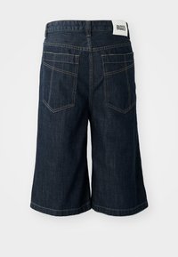 Tamno plave traperice kratke hlače opuštenog kroja, s etiketom na pojasu, dva stražnja džepa i kontrastnim šavovima duž šavova.