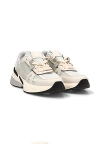 Zapatillas de running de color crema claro con tejido de malla y lengüeta acolchada. Suela negra, acentos texturizados y detalles reflectantes en todo el diseño.