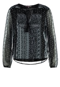 Blusa negra con estampado y mangas largas transparentes, que cuenta con un lazo en el cuello e intrincados diseños en blanco, con un dobladillo curvado en la parte inferior.