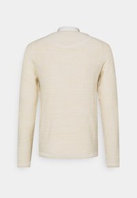 Helles cremefarbenes Langarmshirt mit strukturiertem Finish und rundem Ausschnitt. Verfügt über eine schlichte Naht und eine lockere Passform.