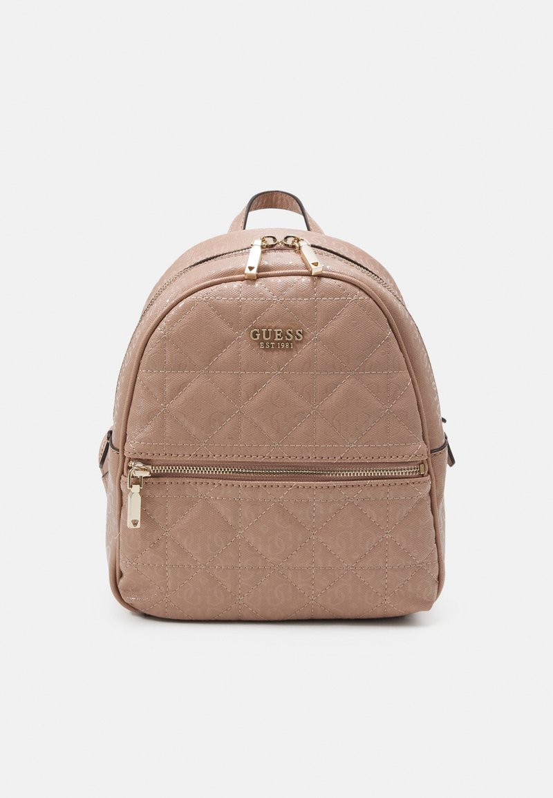 Petit sac à dos beige matelassé avec poche zippée à l'avant, fermetures éclair dorées et logo Guess à l'avant, sur un fond uni.