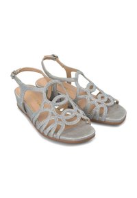 Srebrne klapki na wedge z dekoracyjnym, wyciętym wzorem i akcentami błyszczącymi. Miękkie, teksturowane paski oraz gładka, metaliczna wkładka.