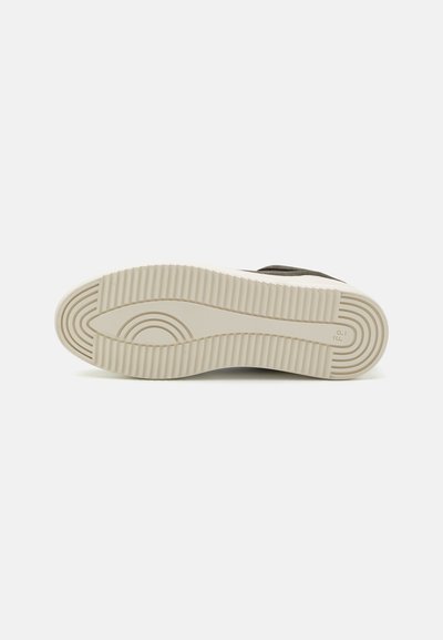 Sneaker sole with a white rubber bottom, featuring horizontal grooves and a rounded pattern. Color is cream with dark accents.