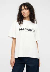 Λευκό υπερμεγέθες t-shirt από βαμβάκι. Διαθέτει μαύρο λογότυπο "ALLSAINTS" στο στήθος και άνετη γραμμή. Φορεμένο με σκουρόχρωμο τζιν.