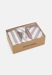 Trois accessoires dans une boîte en carton marron : une cravate rayée et deux paires de boutons de manchette rayés de couleur crème et marron clair.
