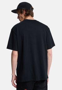 Sort bomulds T-shirt med korte ærmer og en afslappet pasform, der har en glat struktur og ingen synlige mønstre eller detaljer.