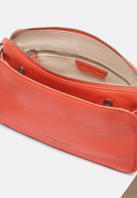 Borsa a tracolla in pelle corallo con chiusura a zip, foderata in tessuto beige, tasca interna e logo stampato sul lato esterno.