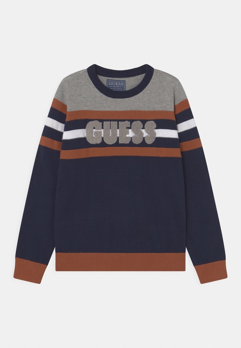 Pull col rond avec des rayures grises, marron, bleu marine et blanches, avec lettrage "GUESS" en relief et texturé sur la poitrine.