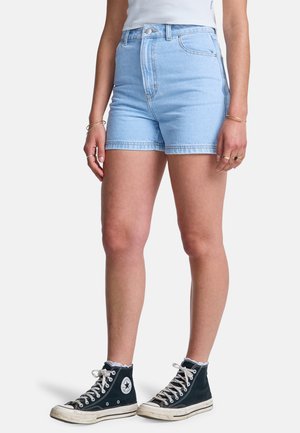 Jasnoniebieskie szorty dżinsowe z wysokim stanem i podwiniętym brzegiem. Noszone z czarnymi wysokimi trampkami z białymi akcentami i logo.
