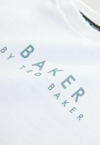 Biele bavlnené tričko s reflexným modrým logom "BAKER by TED BAKER." Hladká textúra, okrúhly výstrih a krátke rukávy.