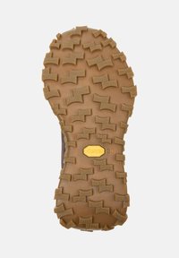 Hnědá podešev Vibram má texturovaný, cik-cak vzorek pro lepší přilnavost, uprostřed s zlatým logem označeným "Vibram 38".