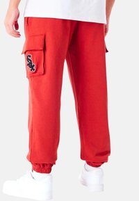 Rode cargo broek met elastische boorden, zijzakken en een zwart geborduurd ontwerp. Gemaakt van een zachte stof, met een comfortabele pasvorm.