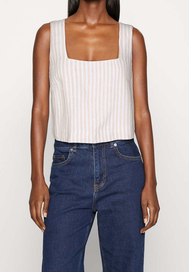 Linblandad linne topp med fyrkantig halsringning, prydd med horisontella krämfärgade och beige ränder, tillsammans med mörkblå högmidjade jeans.