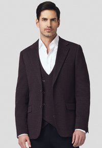 Ciemnoburgundowy żakiet z klapami, pojedynczą kieszenią na piersi i dwiema kieszeniami z przodu. Nosi się go na białej koszuli. 