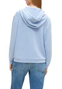 Felpa con cappuccio azzurro chiaro dal taglio morbido e rilassato, con texture soffice e orlo a coste, abbinata a jeans in denim azzurro chiaro.