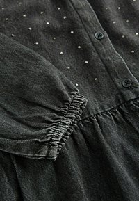 Vestito grigio scuro con bottoni, maniche a sbuffo, polsini elastici, accenti di perline d'argento sparse e dettaglio di tessuto arricciato in vita.