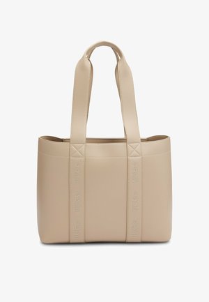 Sac fourre-tout en simili cuir beige avec des accents matelassés, double poignées, et logo "HUGO" embossé sur les côtés. Forme rectangulaire avec une texture lisse.