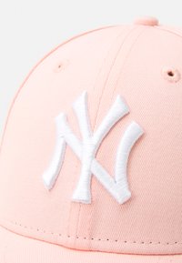 Cappellino da baseball rosa con una forma strutturata, caratterizzato da un grande logo "NY" ricamato in bianco, tessuto testurizzato e fori di ventilazione.