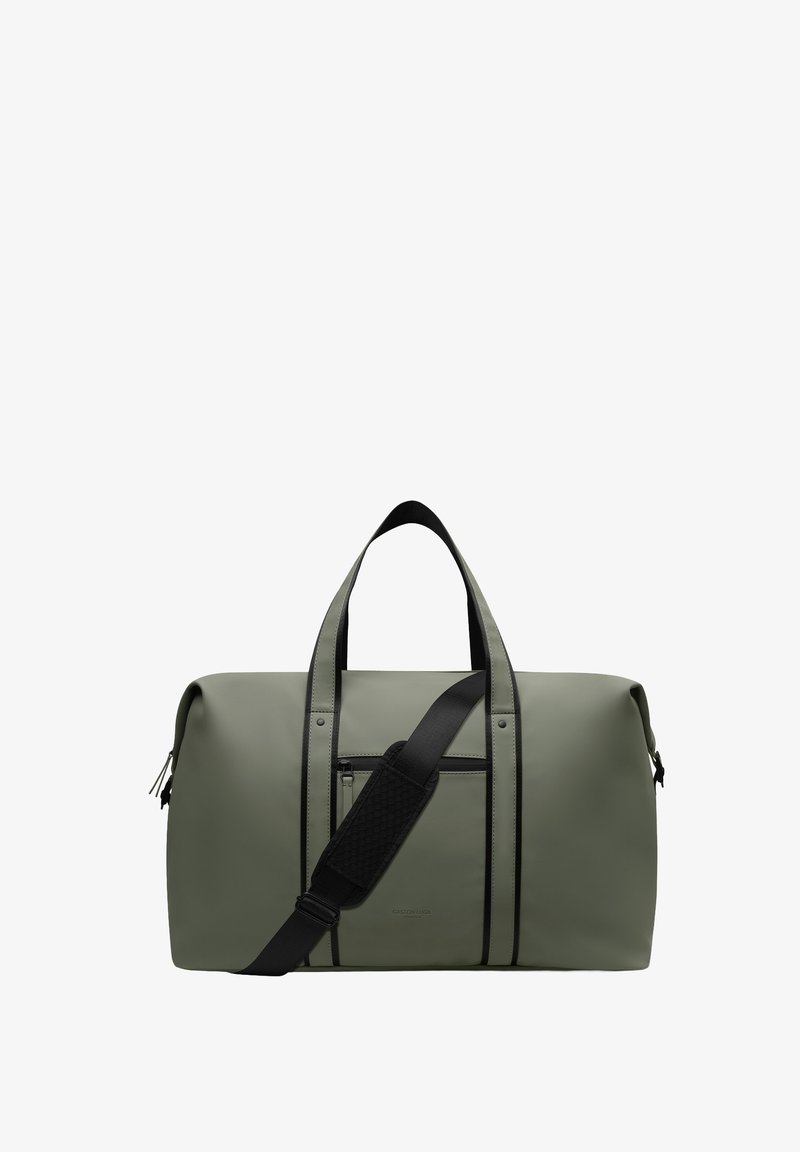 Τσάντα duffel σε ελαιί πράσινο με μαύρες λαβές και ρυθμιζόμενο ιμάντα ώμου, εμπρόσθια τσέπη με φερμουάρ και μινιμαλιστικό σχέδιο.