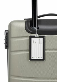Zilveren harde koffer met geprofileerde oppervlakte. Voorzien van een uitschuifbare zwarte handgreep, slot en een aangehechte naamtag. Merk: Wittchen.