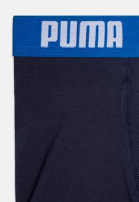 Mornarskoplavi bokserice s rastezljivim pojasom koji ima plavi pojas i bijeli "PUMA" logotip. Mekana, glatka tkanina; standardno šivanje.