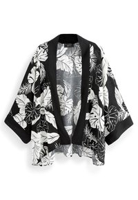 Czarny i biały przezroczysty kimono z intensywnym nadrukiem tropikalnych liści, szerokimi rękawami i solidnym czarnym wykończeniem na brzegach. Otwarty przód.