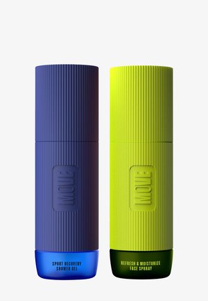 Deux bouteilles cylindriques : une bleue foncée étiquetée "Gel douche de récupération sportive" et une verte brillante étiquetée "Vaporisateur rafraîchissant et hydratant pour le visage". Les deux ont une texture striée.